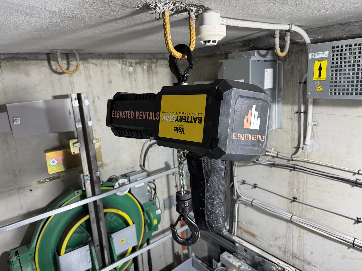 Elevated Rentals branded 1T Yale BatteryStar battery powered chain hoist rigged in a lift machine room